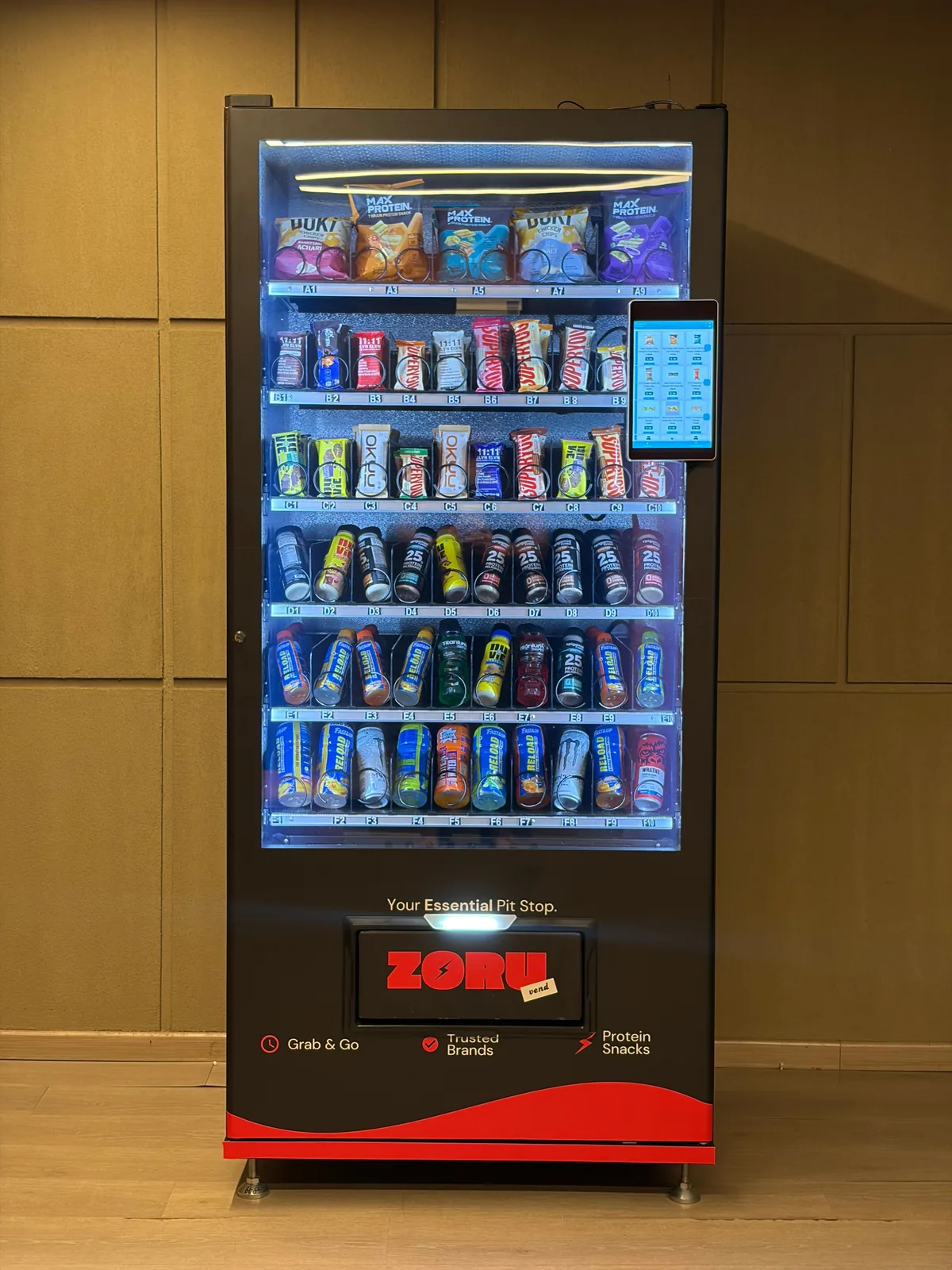 A Zoruvend protein vending machine seen head-on, its lit shelves fully stocked with protein bars, chips, shakes and drinks
