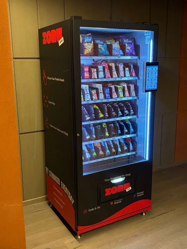 The side panel of a Zoruvend machine listing its three steps: choose your protein snack, scan and pay, collect your snack and train