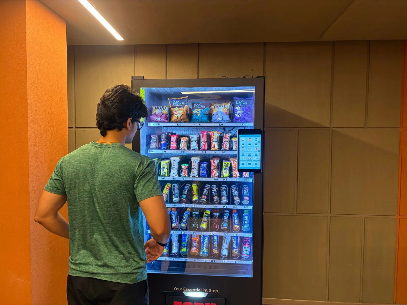 A gym member in training kit standing at a Zoruvend machine, choosing from the lit shelves